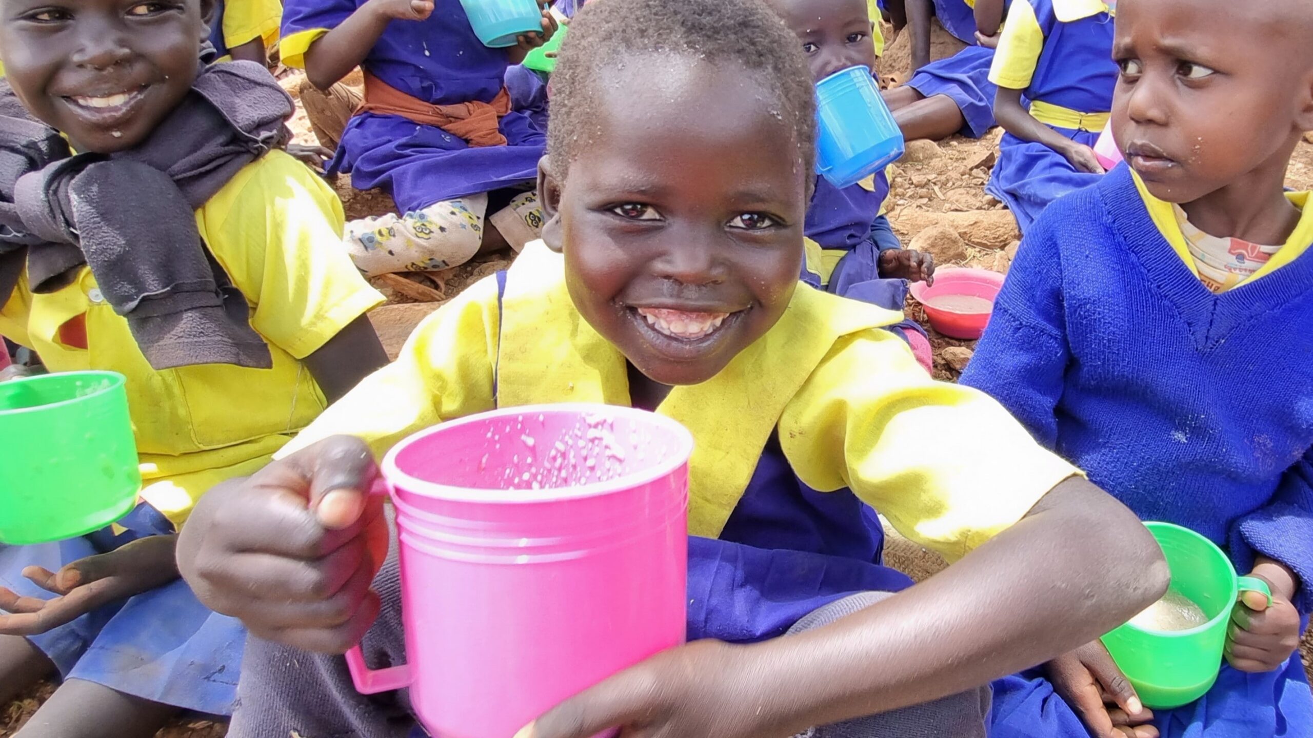A young child holds a pink mug