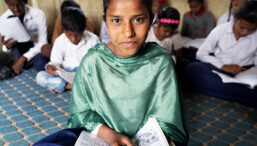 Nepali girl holding a book and smiling at the camera