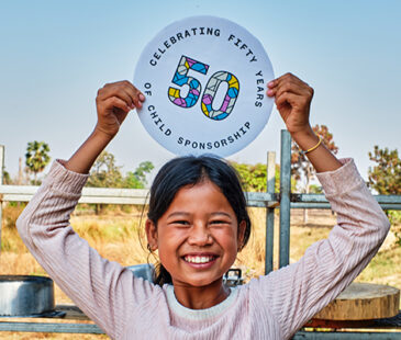 Girl holding 50 Years celebration sign above her head