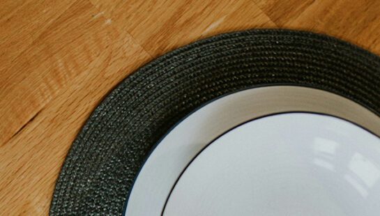 Aerial shot of two dinner plates on green placemats on a wooden table