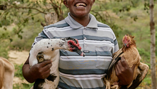 Woman holding two chickens under each arm in Uganda