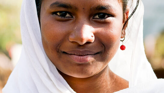 Girl in Nepal wearing white head covering smiling at camera