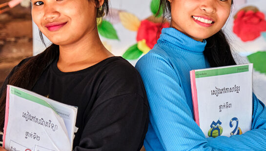 Two girls at school holding books in Cambodia