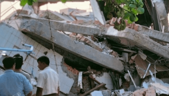 People stand in front of rubble in Myanmar, post-earthquake