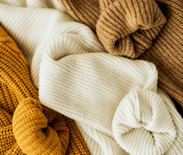 Pile of knitted jumpers in warm coloured tones