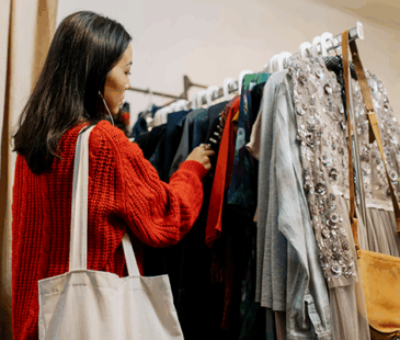 Woman wearing red jumper browsing clothing rack