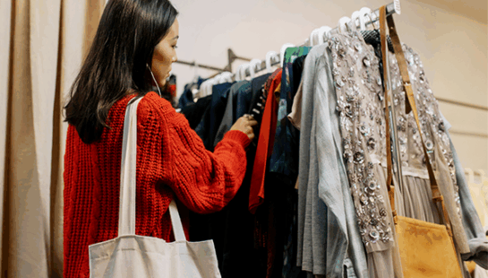 Woman wearing red jumper browsing clothing rack