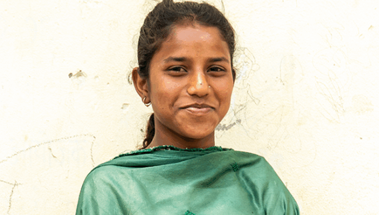 Nepali girl, Khusnaj, smiling directly at the camera. She's wearing a green shawl.